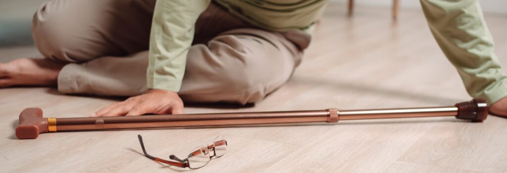 Image of a senior after a fall with a cane and a pair of glasses.