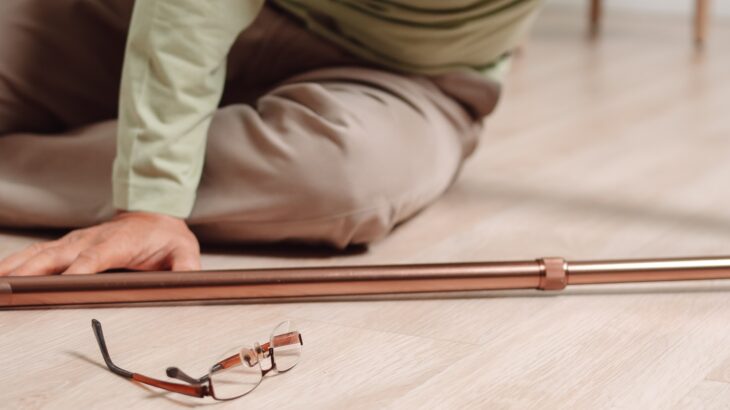 Image of a senior after a fall with a cane and a pair of glasses.